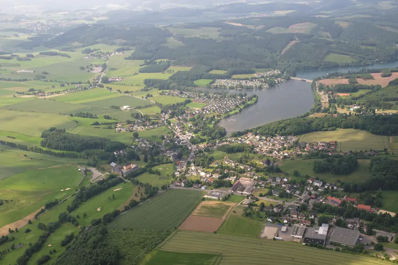 Sorpesee no gaisa, ar Amecke ciemu tā austrumu krastā un mežainajiem Sauerlandes pauguriem ap to
