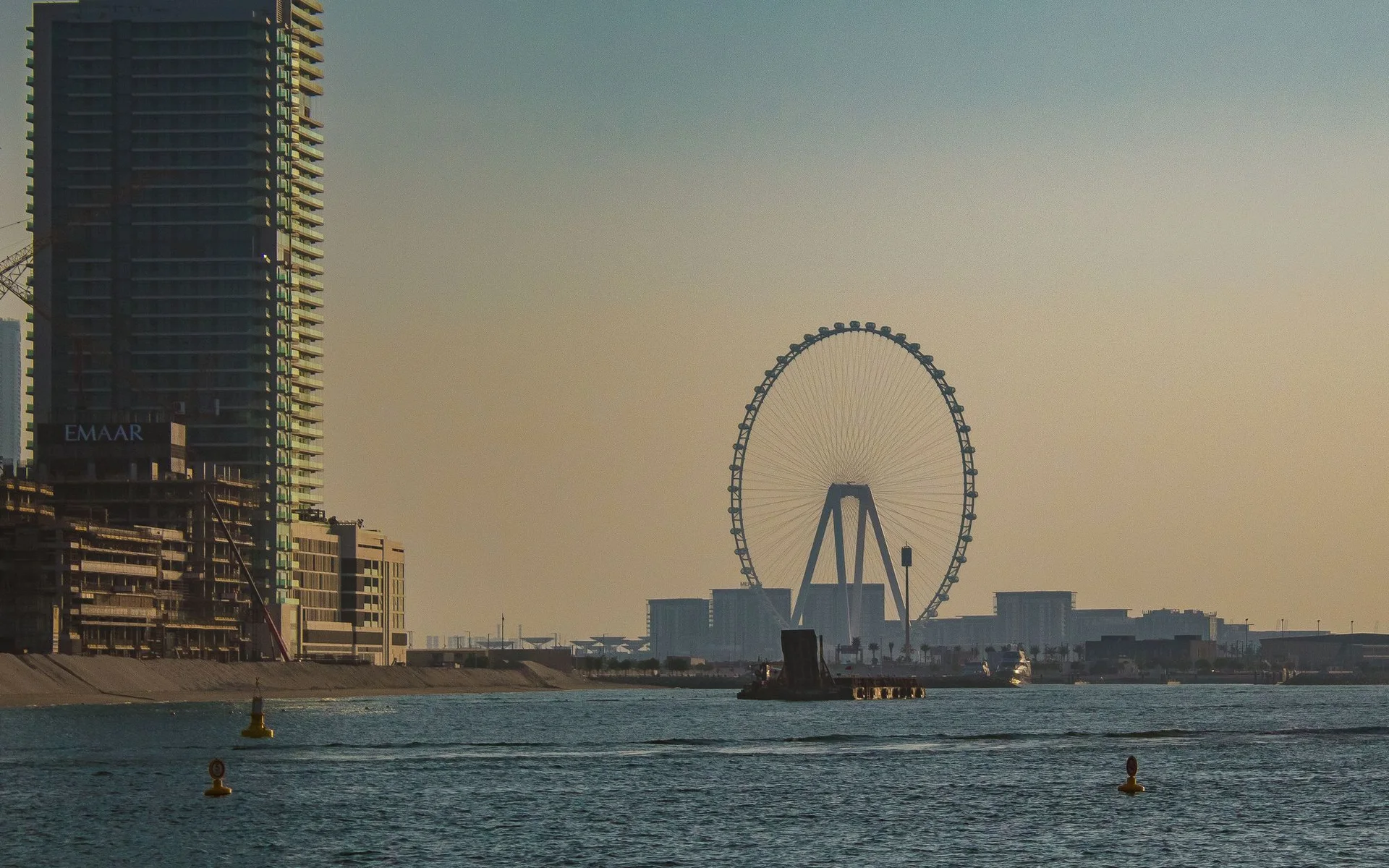 Dubaijas siluets ar milzu ratu saulrieta laikā