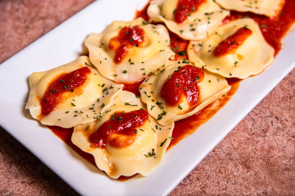 Piemēra fotoattēls: Ravioli ar tomātu mērci un garšaugiem uz baltas šķīvja